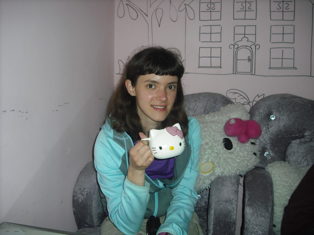 Drinking tea out of my Hello Kitty mug sitting against my Hello Kitty cushion. >^..^<