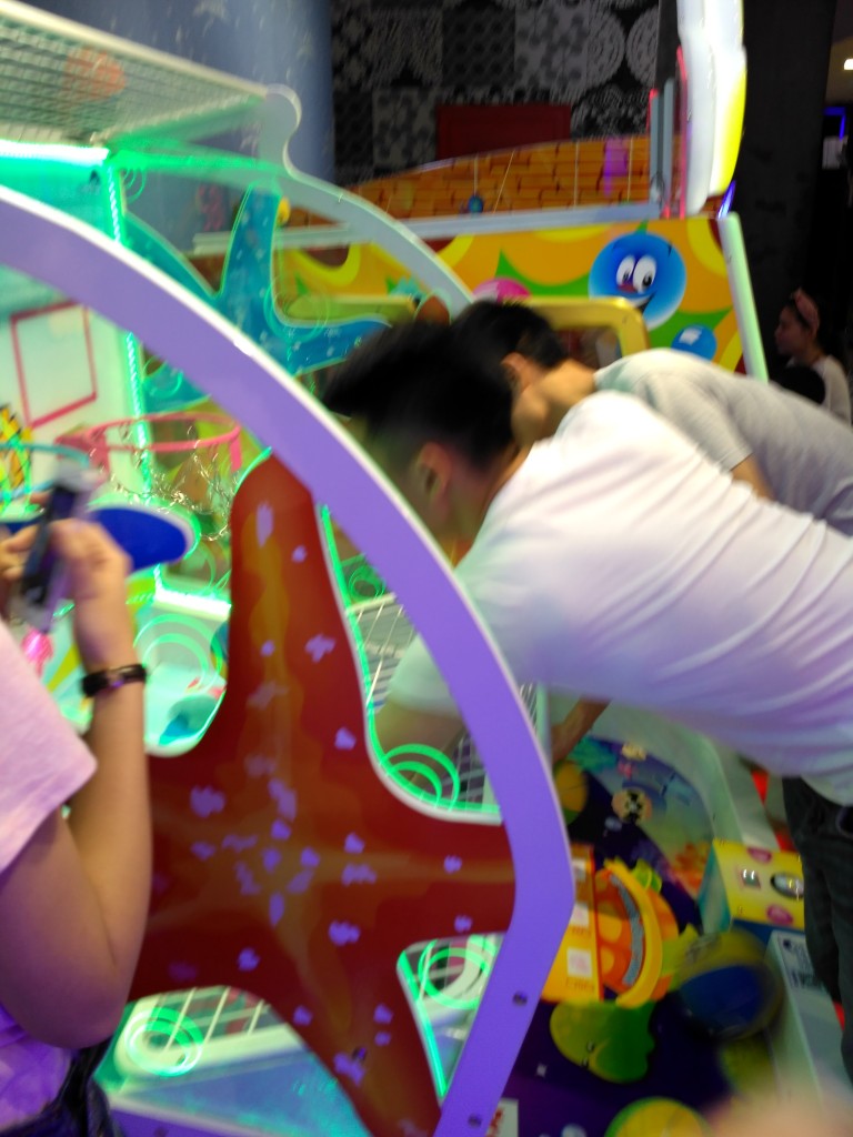 Jessica's friends are goofballs. They're killing time waiting for the movie by dunking basketballs as fast as they can on the children's arcade game.