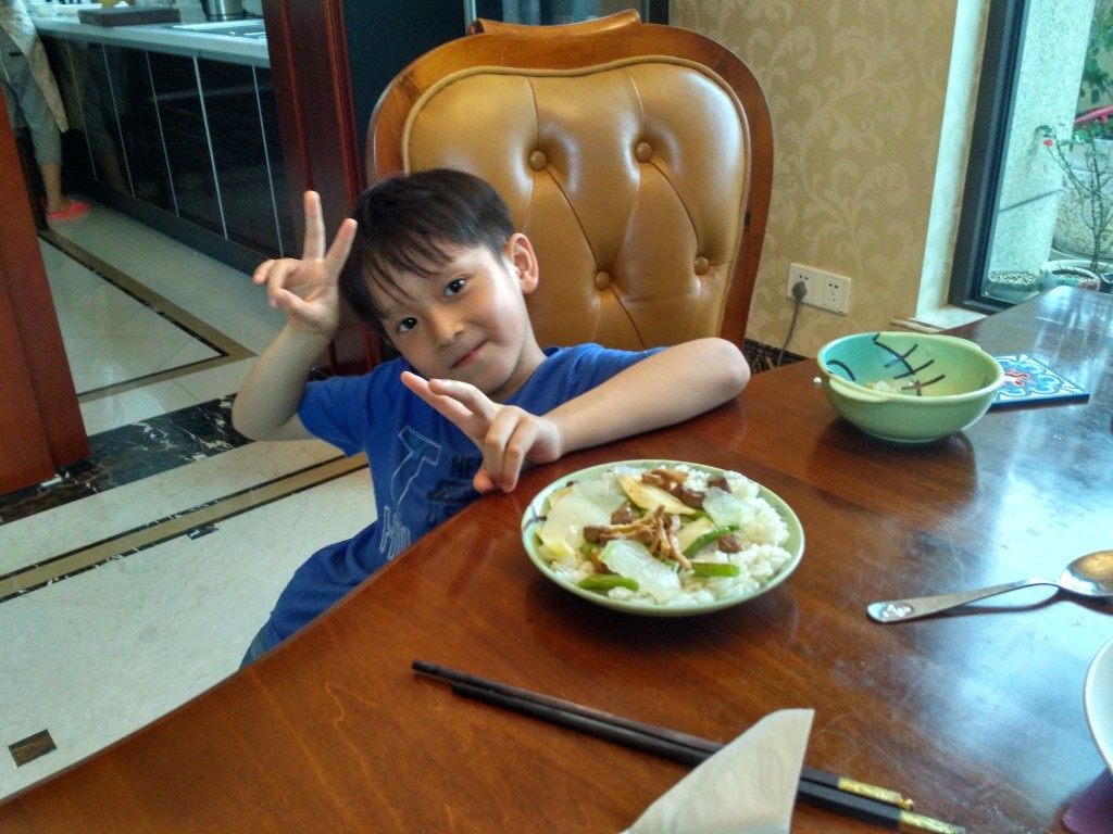 Jony playing with his food at dinner.  He has shaped his rice, meat, and veggies into a "pizza".