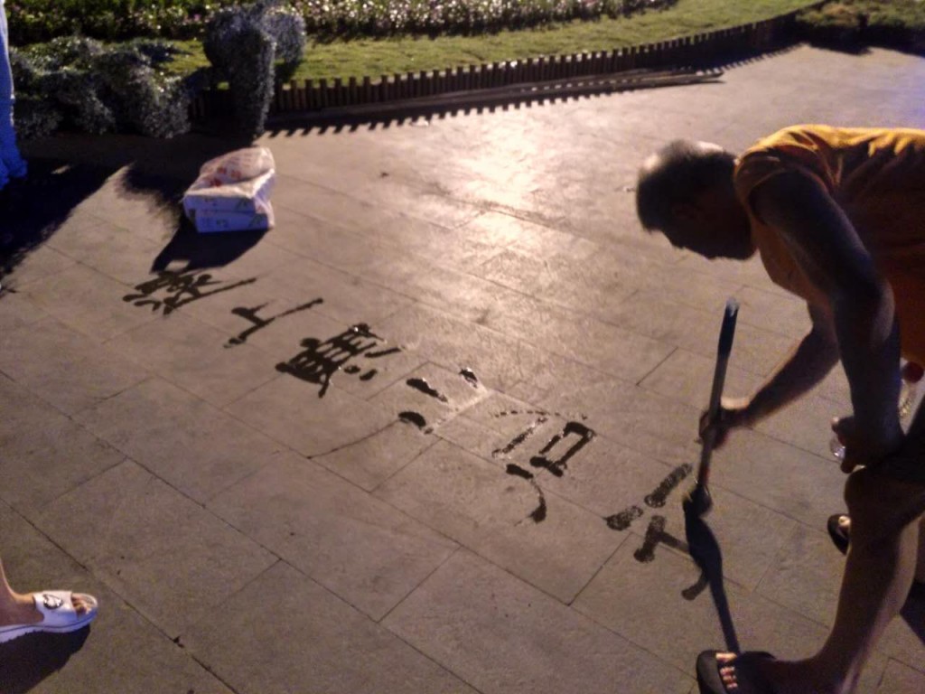 Old men writing Chinese calligraphy with water on the plaza pavement. Everyone has a hobby.