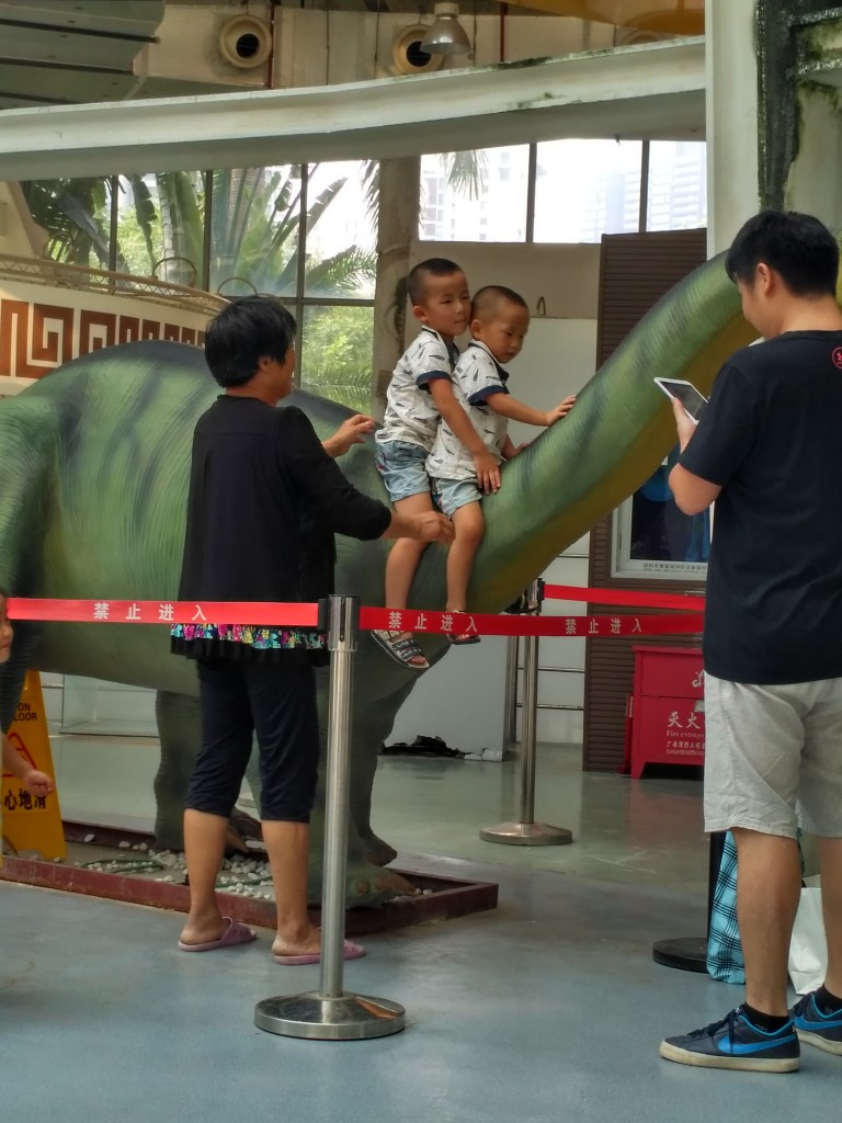 What does that red ribbon mean? Nothing, apparently. Grandma is helping the grand kids ride the dino...