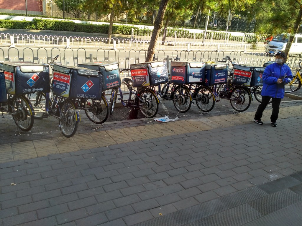 A fleet of pizza delivery bikes parked outside